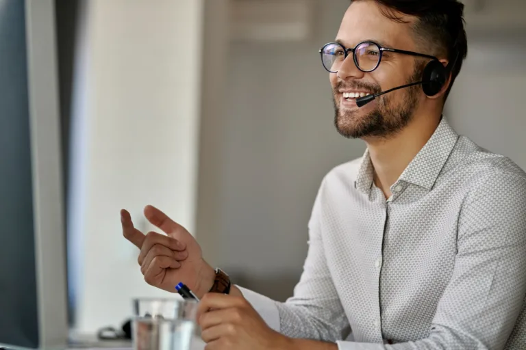 agente de call center feliz usando computador enquanto se comunica com clientes e trabalha no escritorio e1756425664829